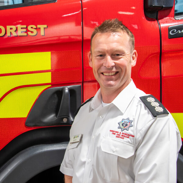 Station Commander in uniform standing in front of fire engine