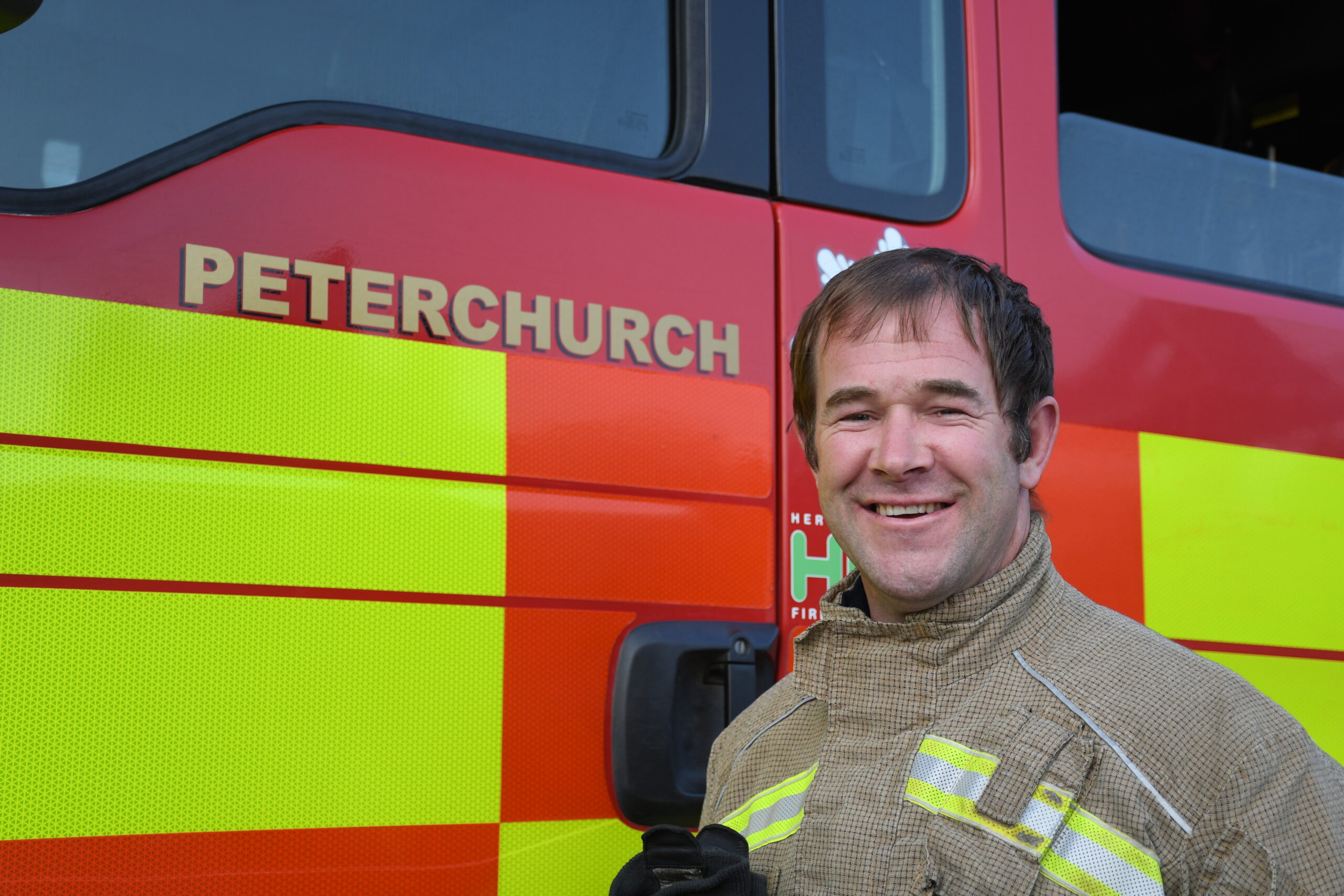 Firefighter standing to the side of a fire engine from Peterchurch.