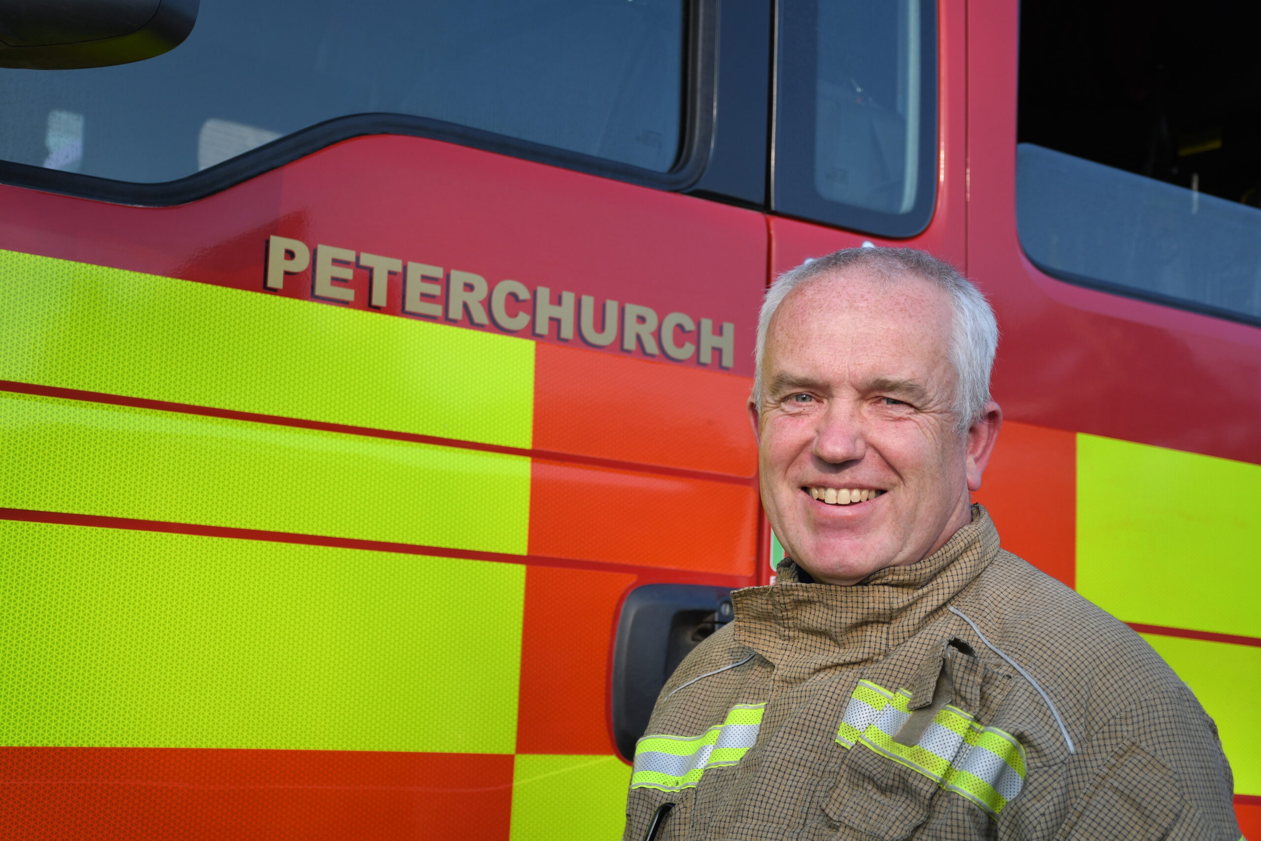 Firefighter in uniform in front of fire engine