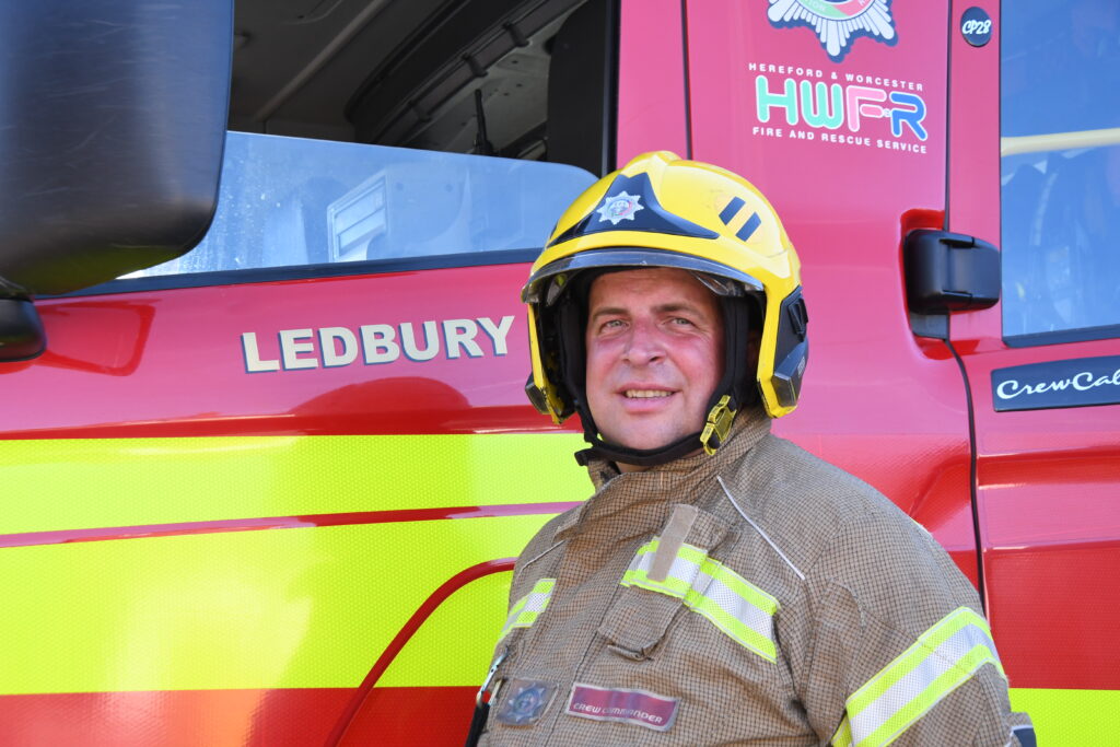 Firefighter in yellow helmet standing in front of fire engine