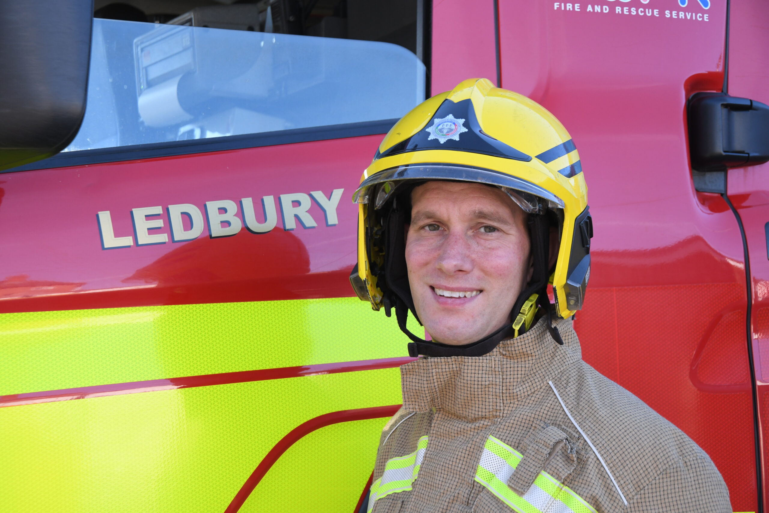 Fire fighter in yellow helmet in front of fire engine