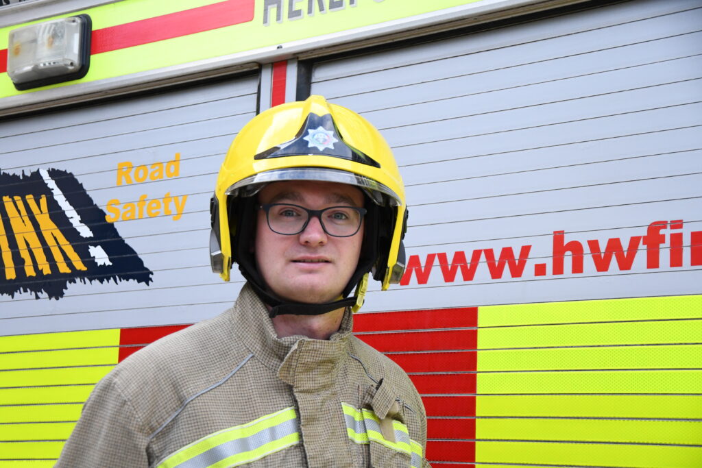 Firefighter on yellow helmet in front of fire engine